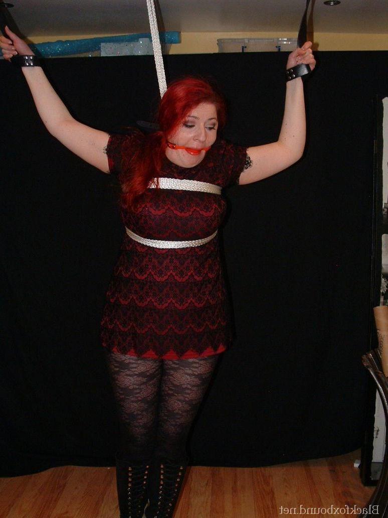 16P Pale redhead is silenced with a gag while restrained by her wrists in clothes