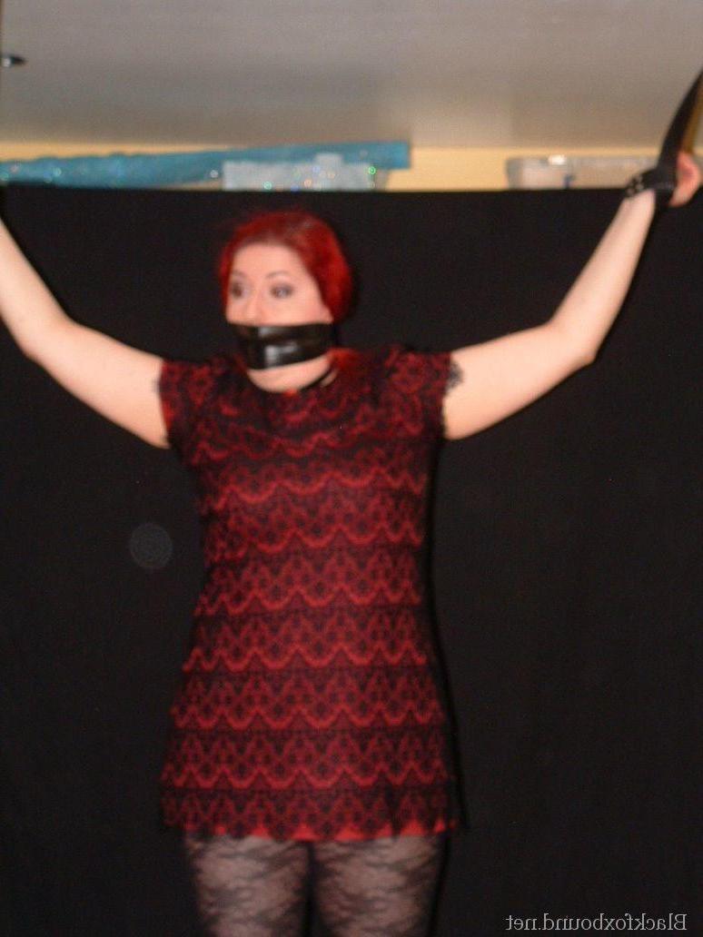 16P Pale redhead is silenced with a gag while restrained by her wrists in clothes