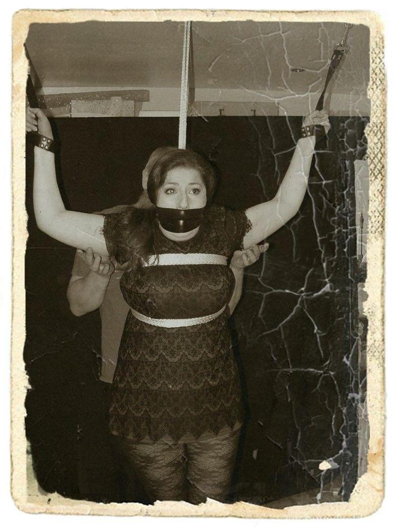 16P Pale redhead is silenced with a gag while restrained by her wrists in clothes