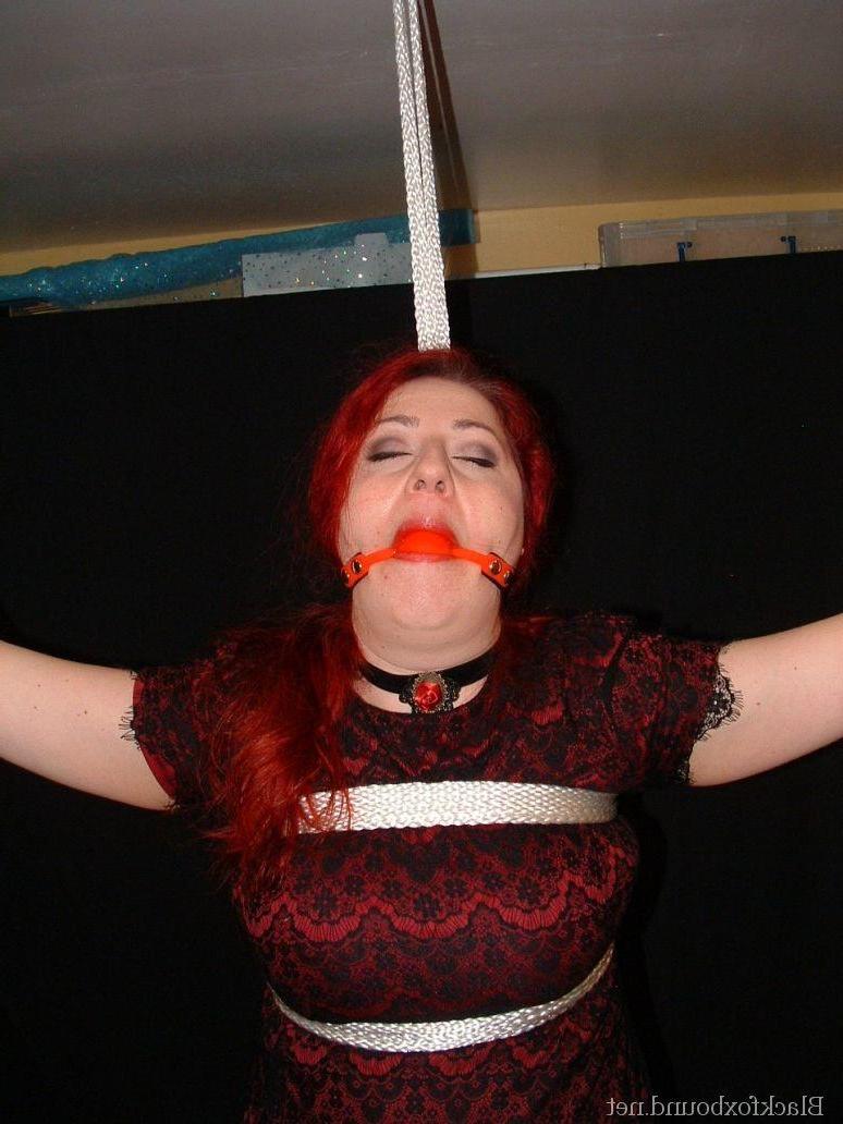 16P Pale redhead is silenced with a gag while restrained by her wrists in clothes