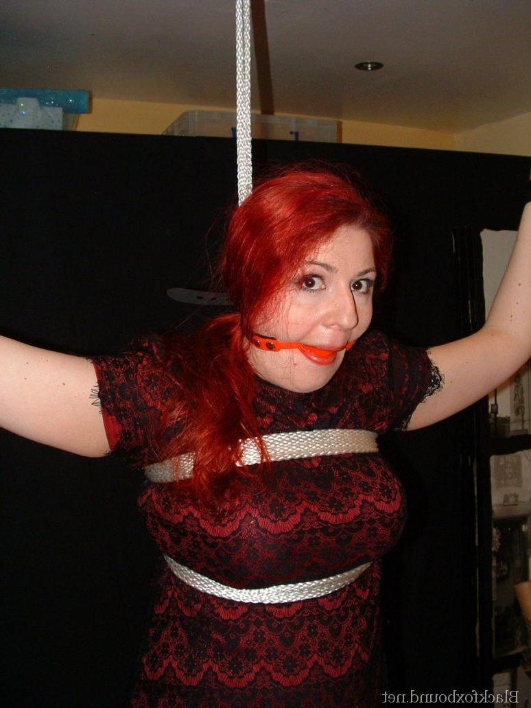 16P Pale redhead is silenced with a gag while restrained by her wrists in clothes