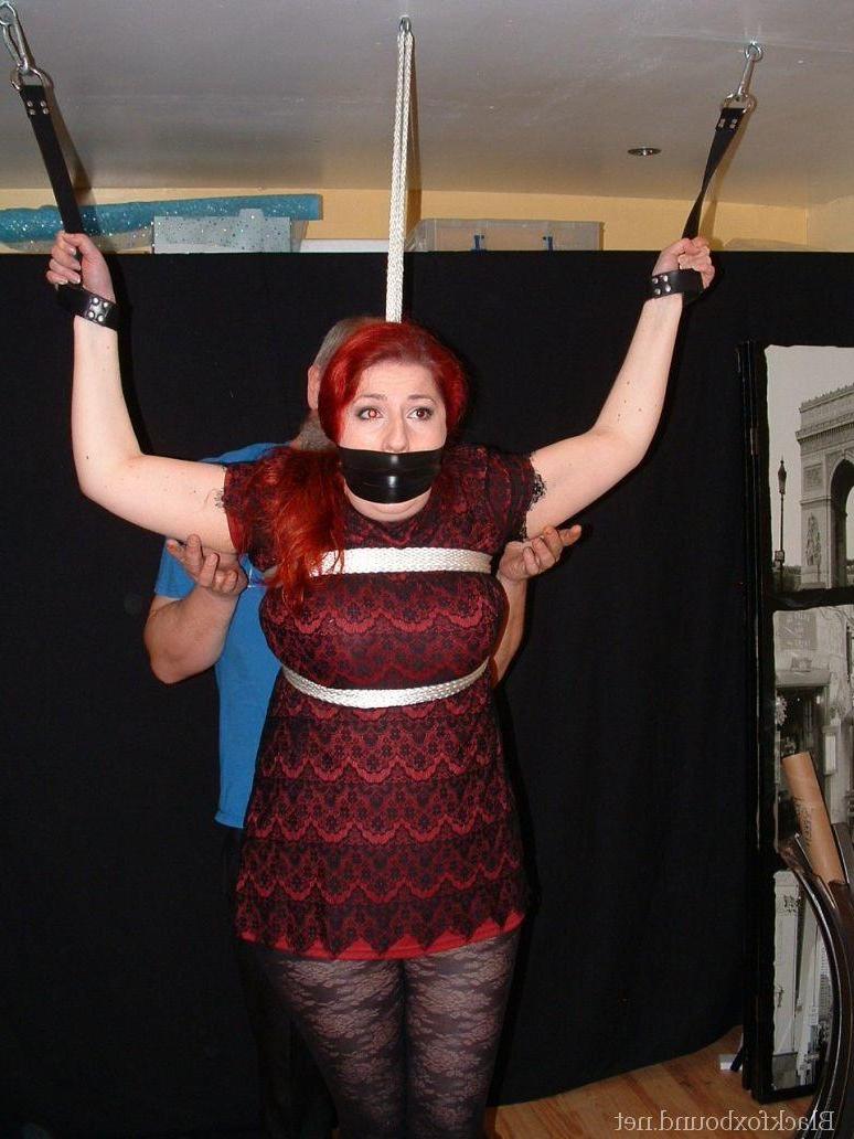 16P Pale redhead is silenced with a gag while restrained by her wrists in clothes