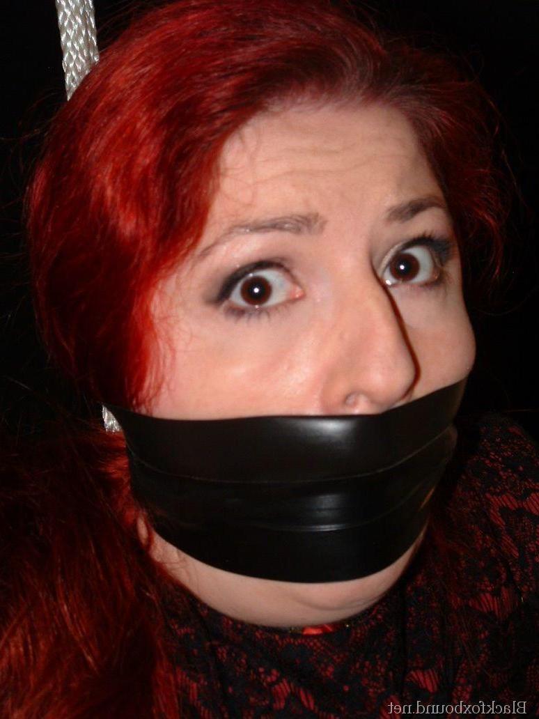 16P Pale redhead is silenced with a gag while restrained by her wrists in clothes