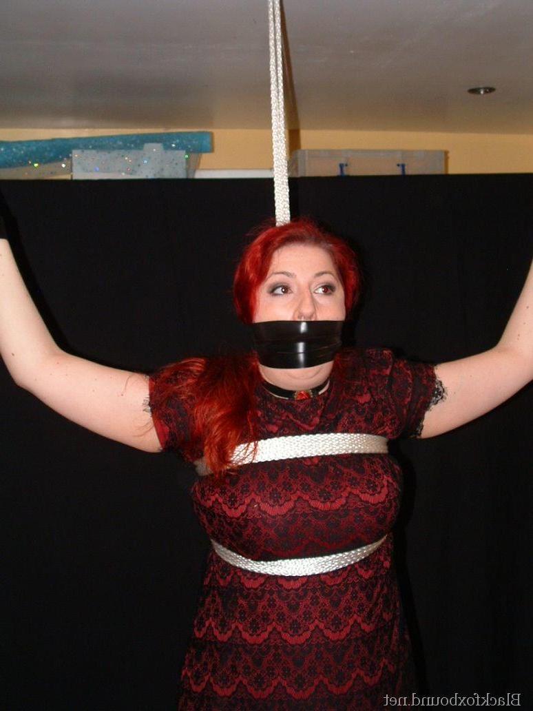 16P Pale redhead is silenced with a gag while restrained by her wrists in clothes