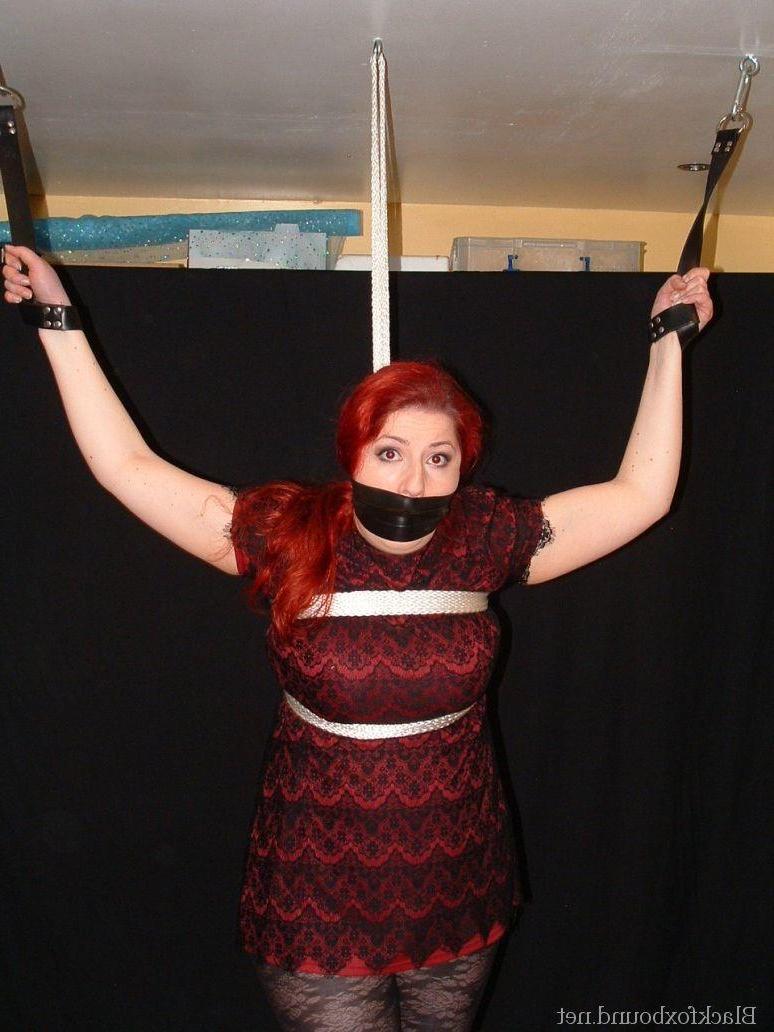16P Pale redhead is silenced with a gag while restrained by her wrists in clothes