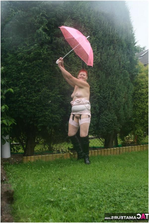 20P 年配の赤毛のヴァルガスミック露出モデルがブロリーを持ちながら雨の中でヌード