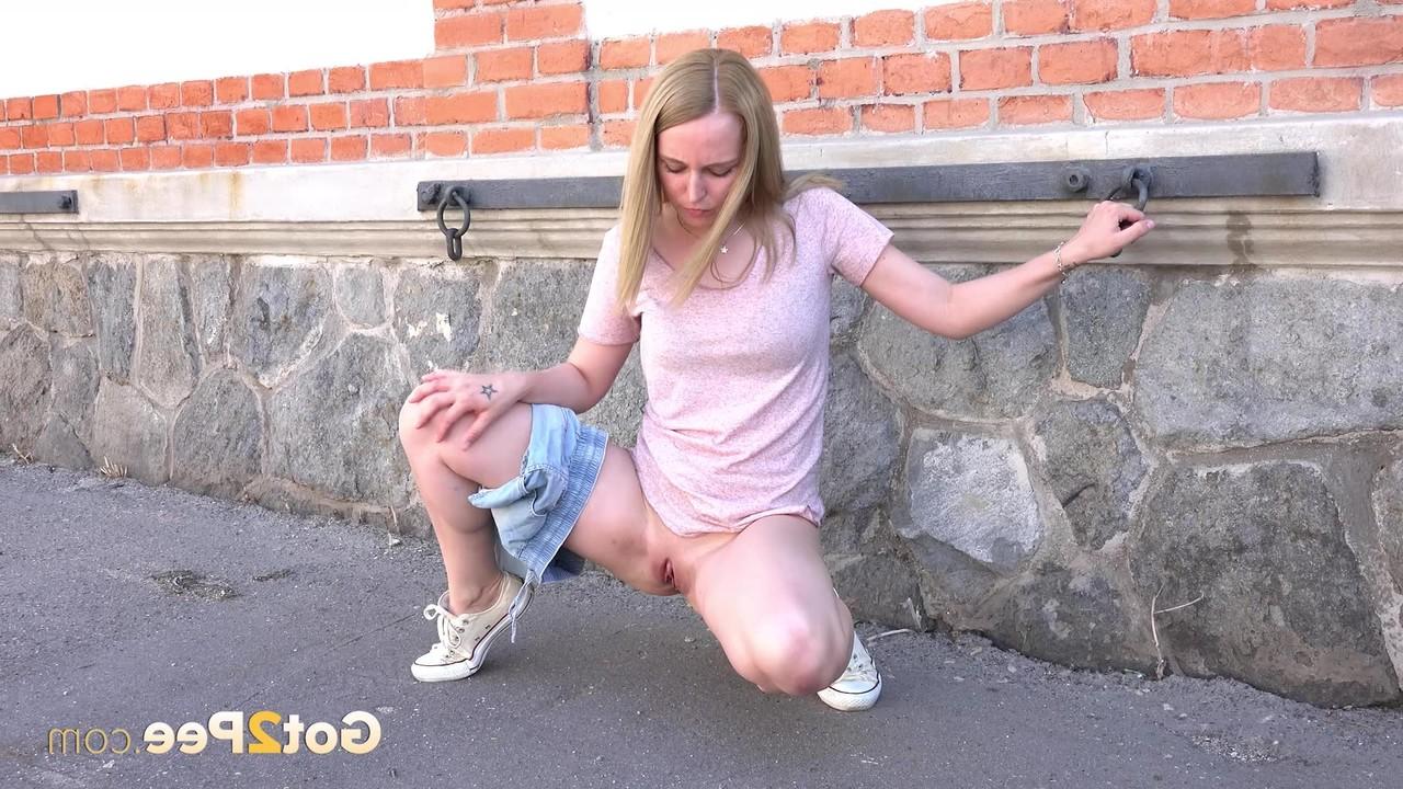 15P Blondes Mädchen zieht ihre Jeansshorts aus, um hinter einem Gebäude dringend zu pinkeln