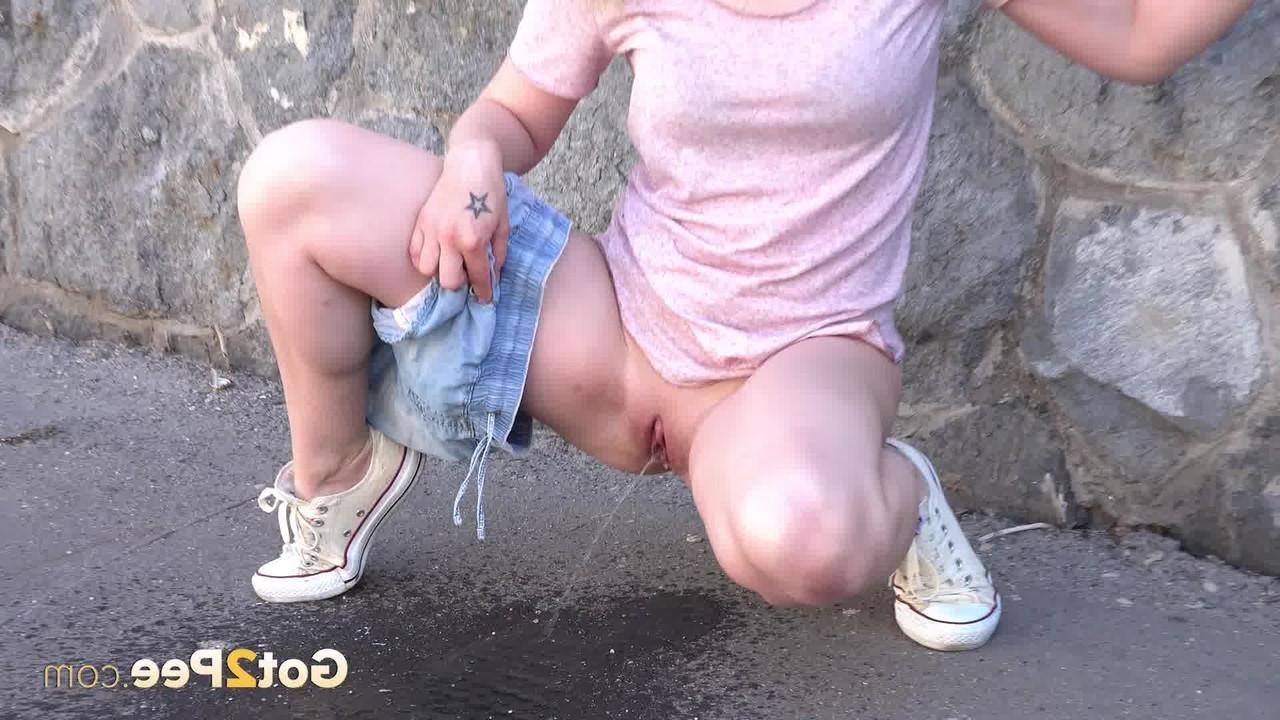15P Blondes Mädchen zieht ihre Jeansshorts aus, um hinter einem Gebäude dringend zu pinkeln