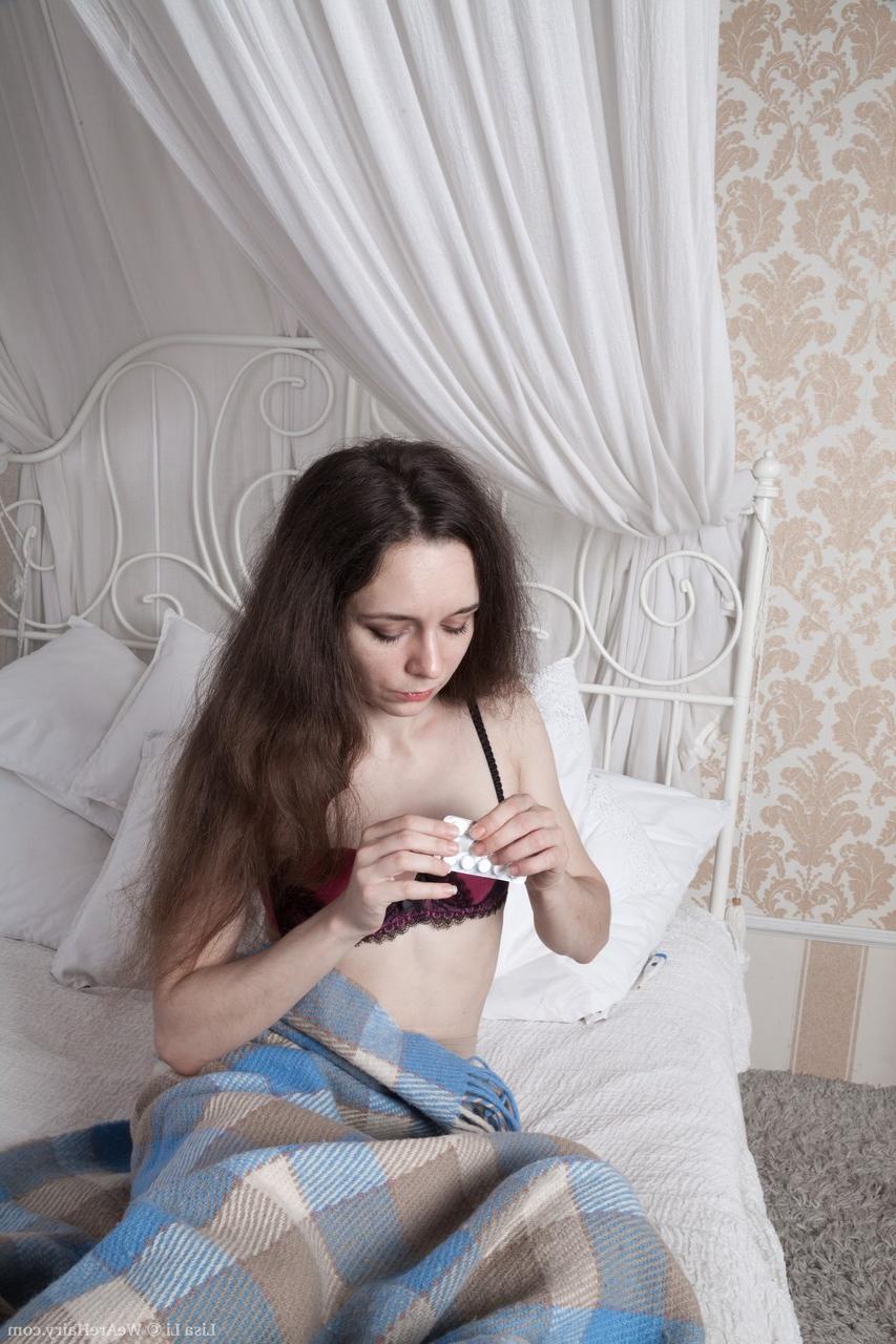 17P Das dünne brünette Babe Lisa Li posiert auf dem Bett und spielt mit ihrem Biber