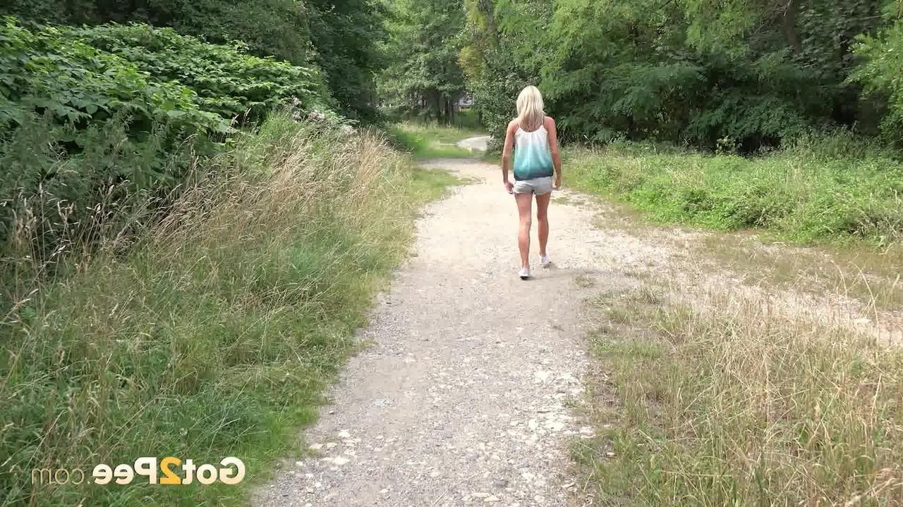 15P A loira Claudia Macc mija em uma trilha durante o dia