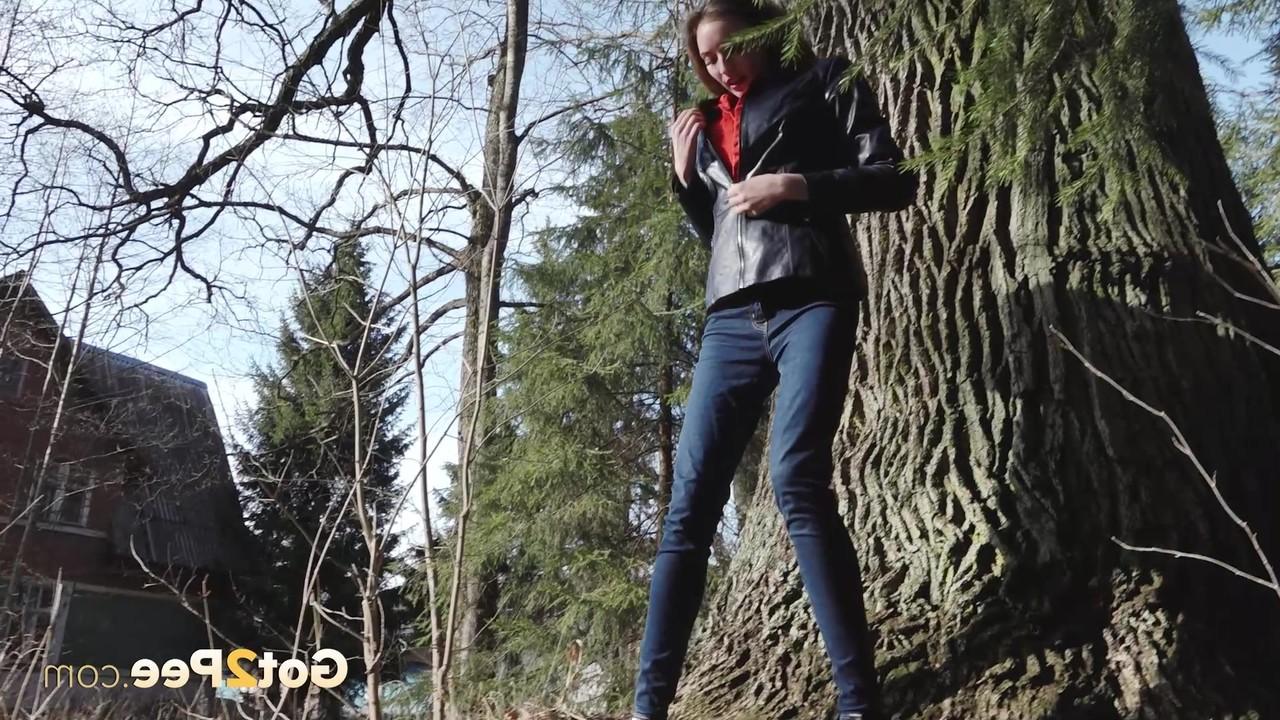 15P A garota branca Vika Lita abaixa a calça jeans para mijar na frente de uma velha árvore