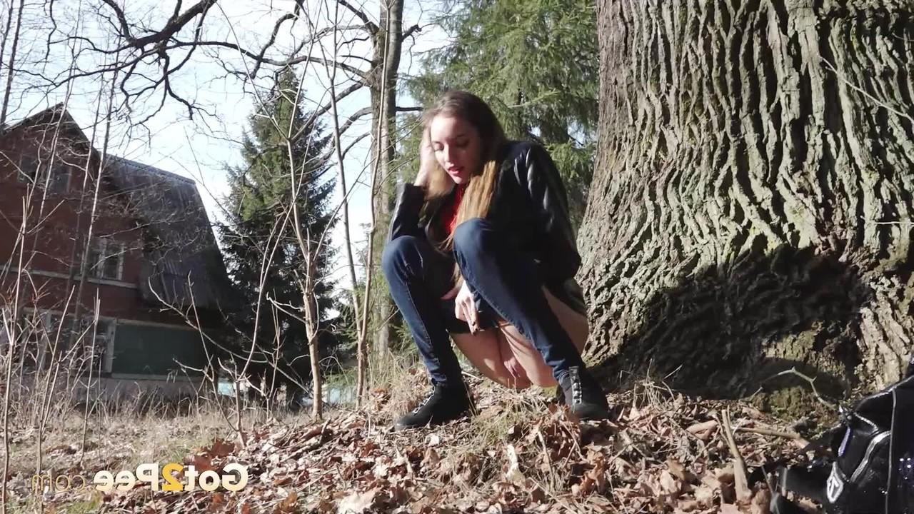 15P A garota branca Vika Lita abaixa a calça jeans para mijar na frente de uma velha árvore