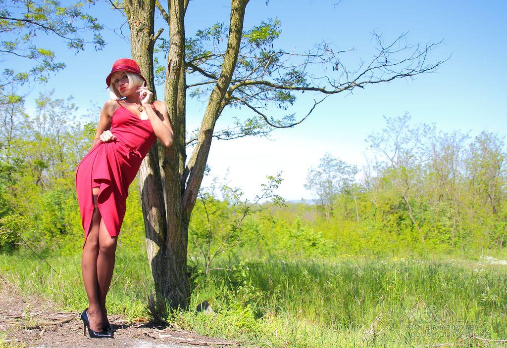 15P Blonde MILF exposes her tits and pussy against a tree in nylons