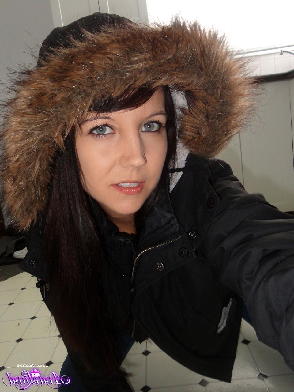 15P Andi Land, jeune amateur, se prend en photo sur le sol de sa cuisine, vêtue d'un manteau d'hiver.
