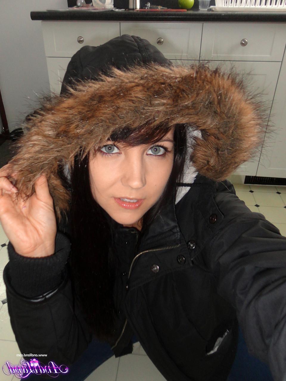15P Andi Land, jeune amateur, se prend en photo sur le sol de sa cuisine, vêtue d'un manteau d'hiver.