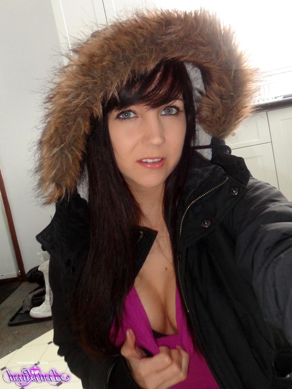 15P Andi Land, jeune amateur, se prend en photo sur le sol de sa cuisine, vêtue d'un manteau d'hiver.