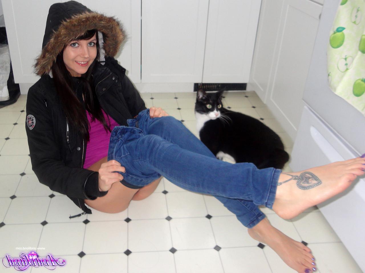 15P Andi Land, jeune amateur, se prend en photo sur le sol de sa cuisine, vêtue d'un manteau d'hiver.