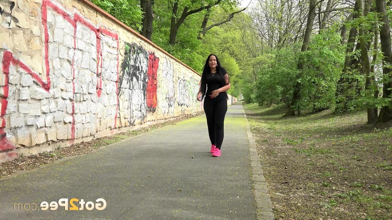 15P A garota morena Lolita Black mija em um caminho pavimentado enquanto sai para passear