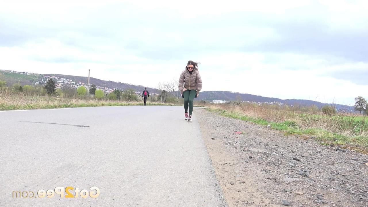 15P Caucasian girl Barbe takes a pee on a paved road during the day