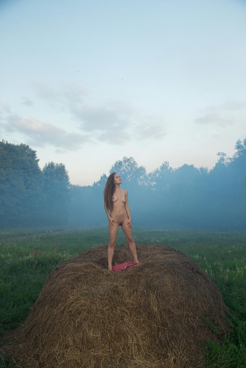 20P Glamorous babe Arina G strips in a bale of hay and poses naked in the mist