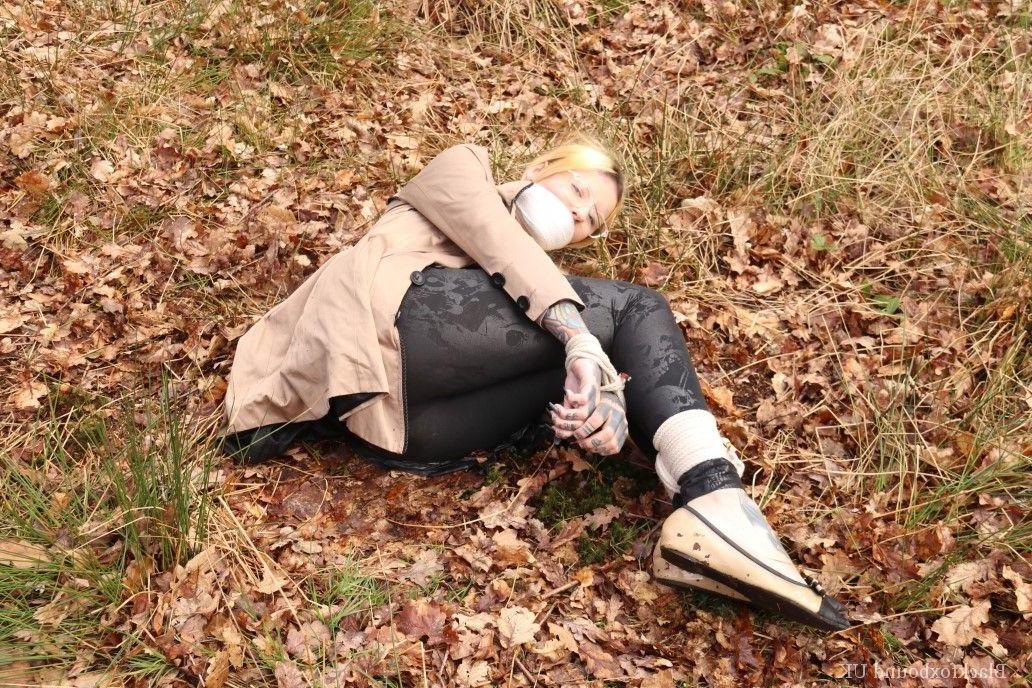 16P Bekleidete Frau wird im Wald geknebelt an Handgelenken und Knöcheln gefesselt