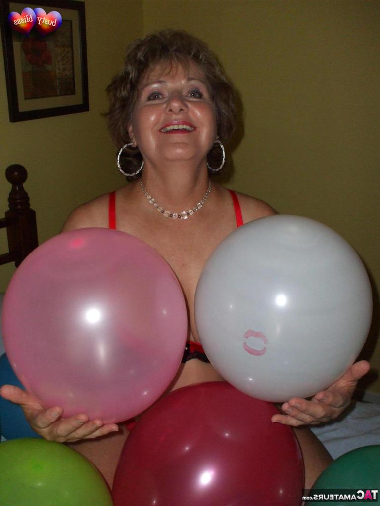 20P Busty Bliss, femme mûre, se met seins nus sur son lit en jouant avec des ballons.