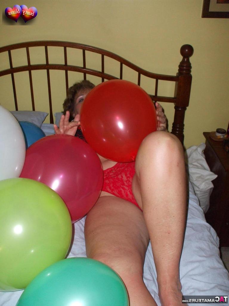 20P Busty Bliss, femme mûre, se met seins nus sur son lit en jouant avec des ballons.