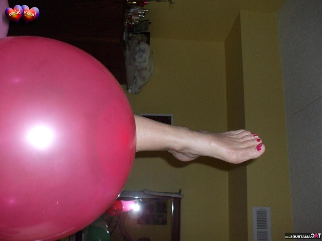 20P Busty Bliss, femme mûre, se met seins nus sur son lit en jouant avec des ballons.