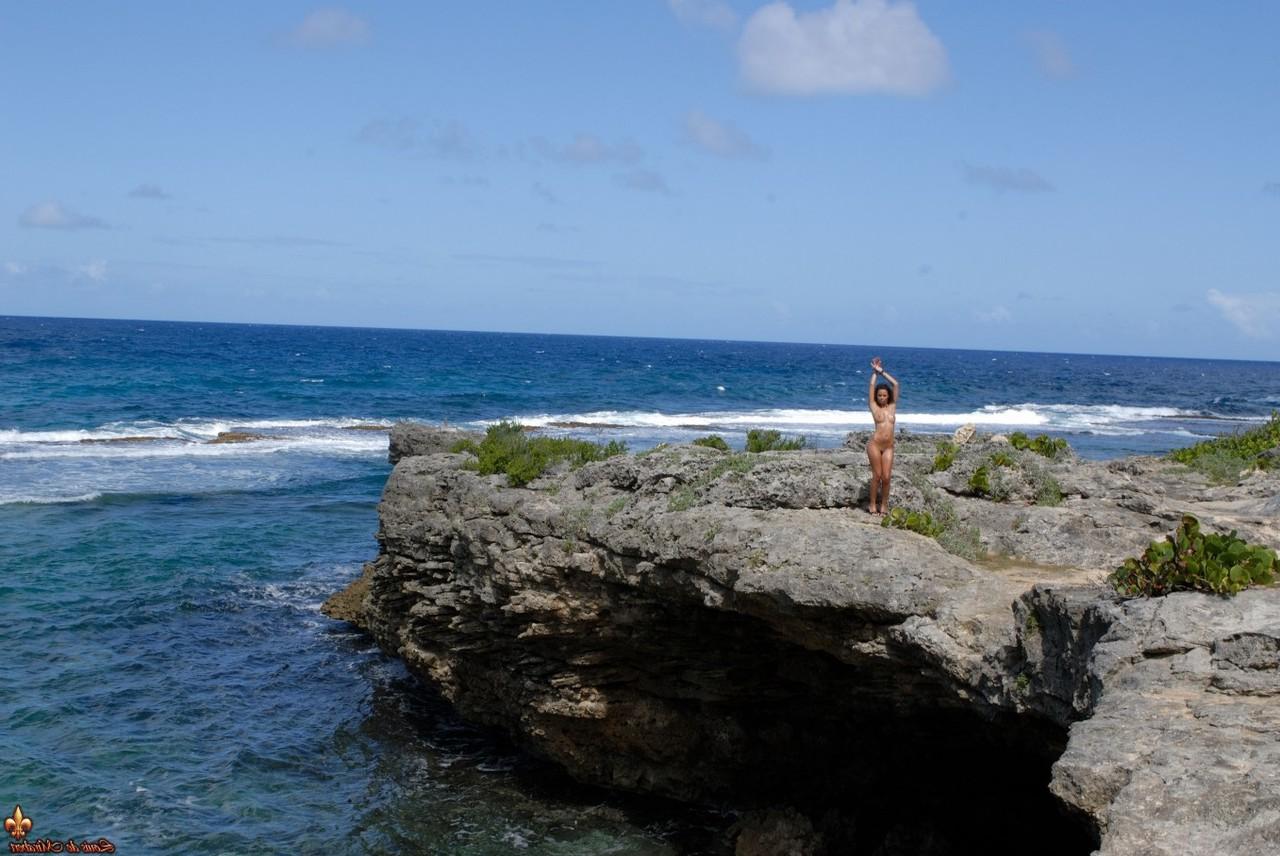 16P Solo model Corail removes a swimsuit to pose naked on an oceanside cliff