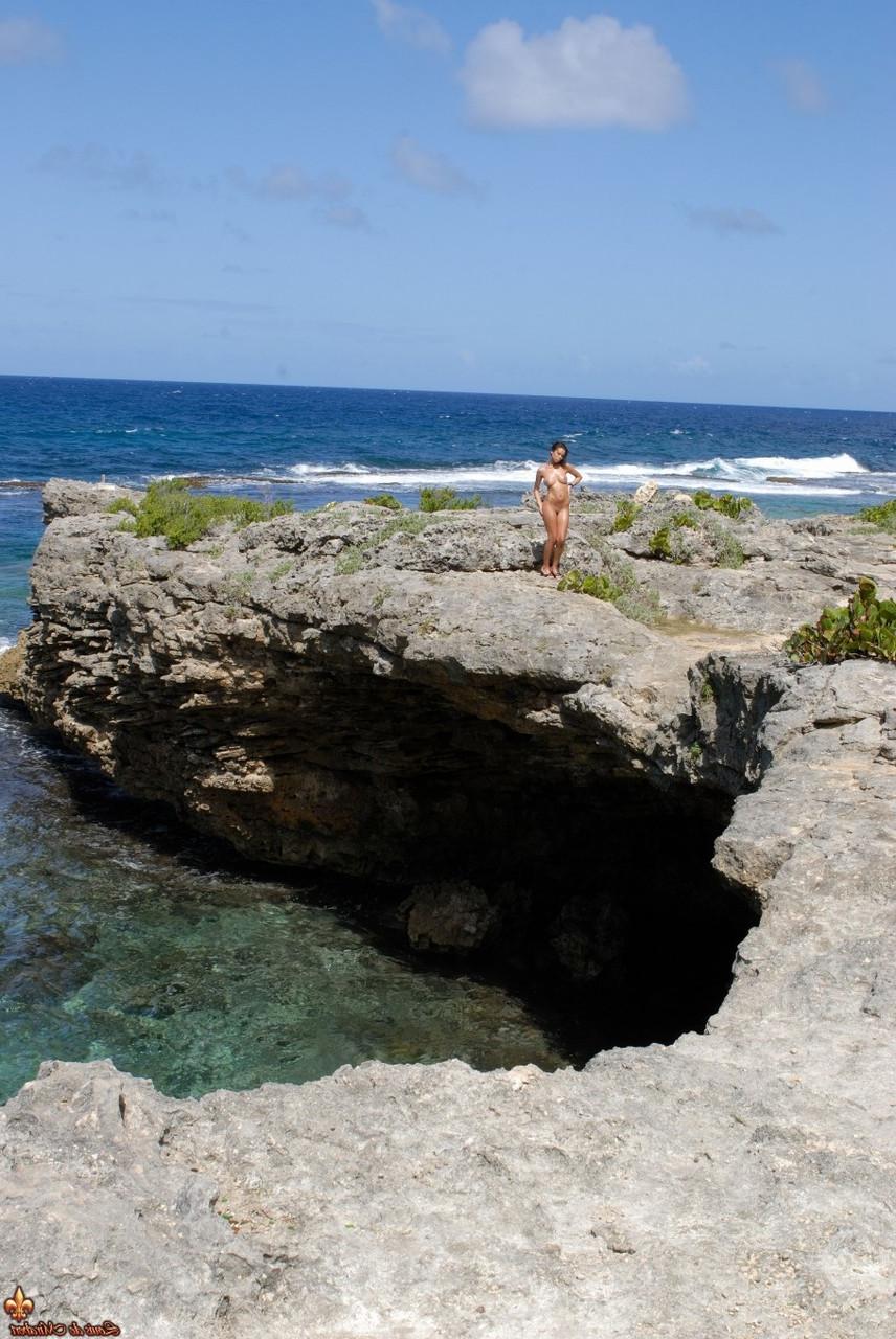 16P Solo model Corail removes a swimsuit to pose naked on an oceanside cliff