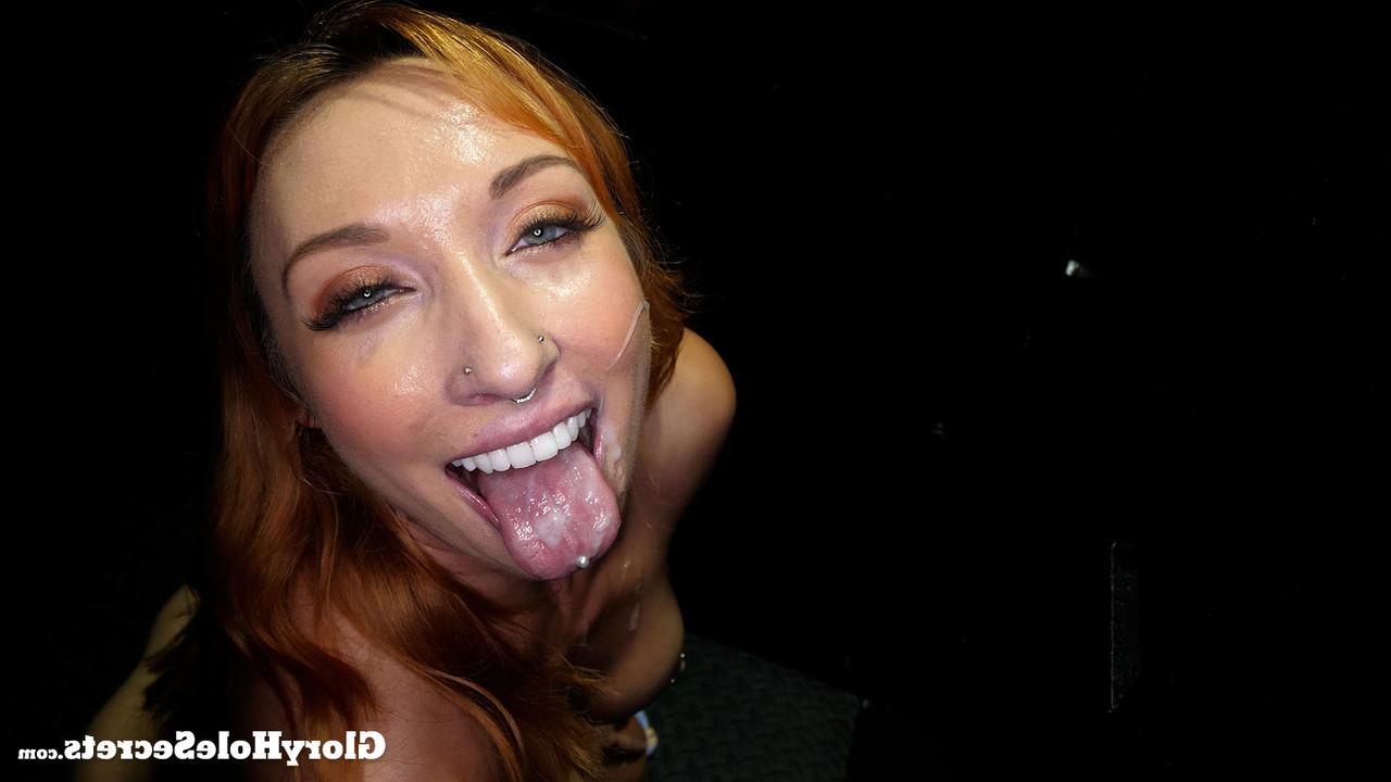 15P Redheaded chick Daisie Belle sucks the cum from cocks at a gloryhole