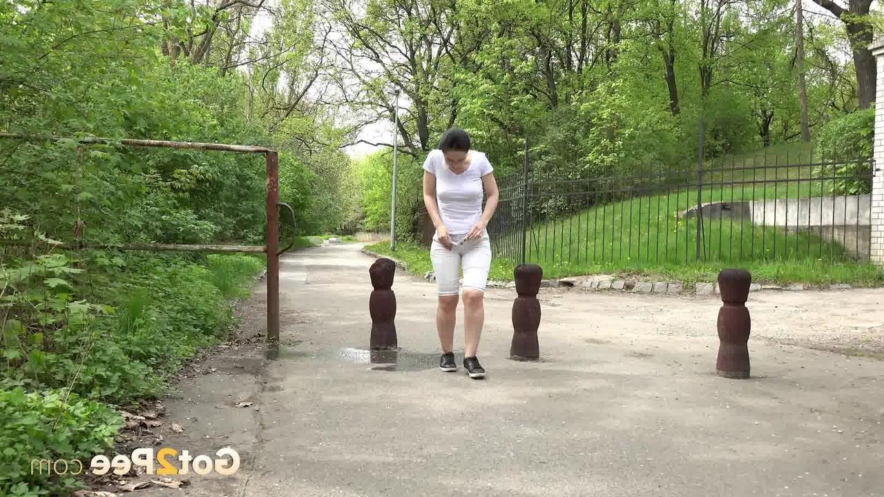 15P Chica de pelo oscuro orina en la vía pública a mitad del día
