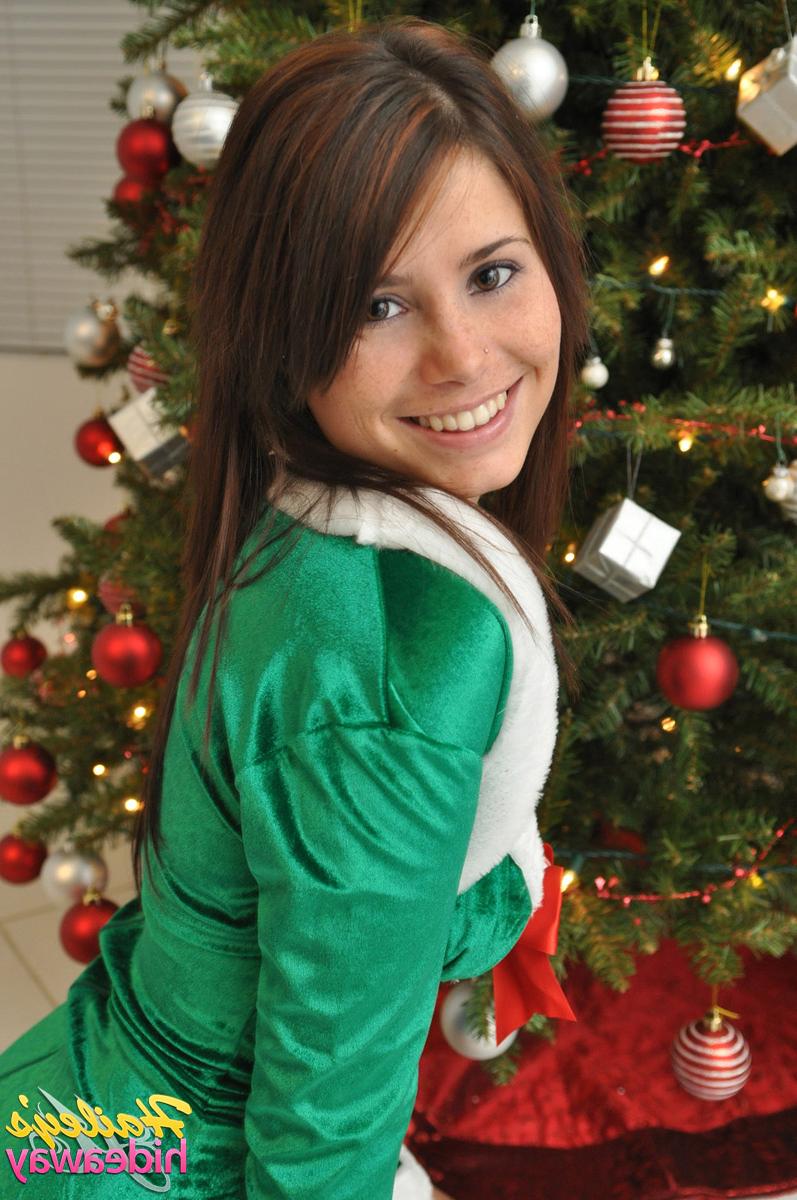 12P L'elfe de Noël amateur Hailey soulève sa jupe moulante pour montrer son cul sexy près de l'arbre.