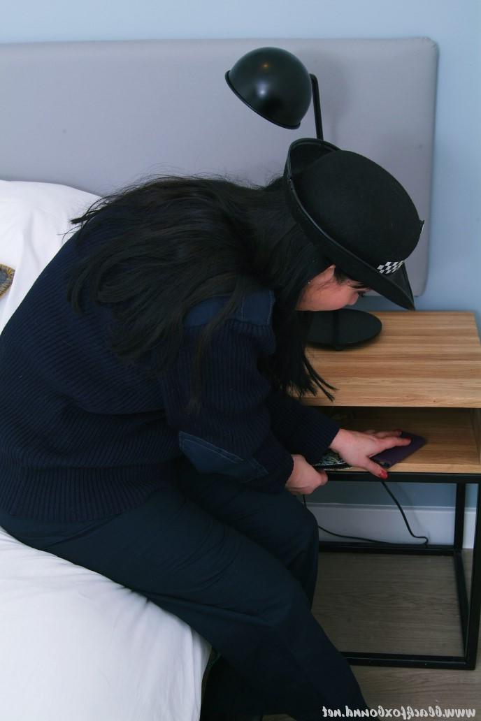 16P Mujer policía de cabello oscuro se encuentra atada a una silla con su uniforme