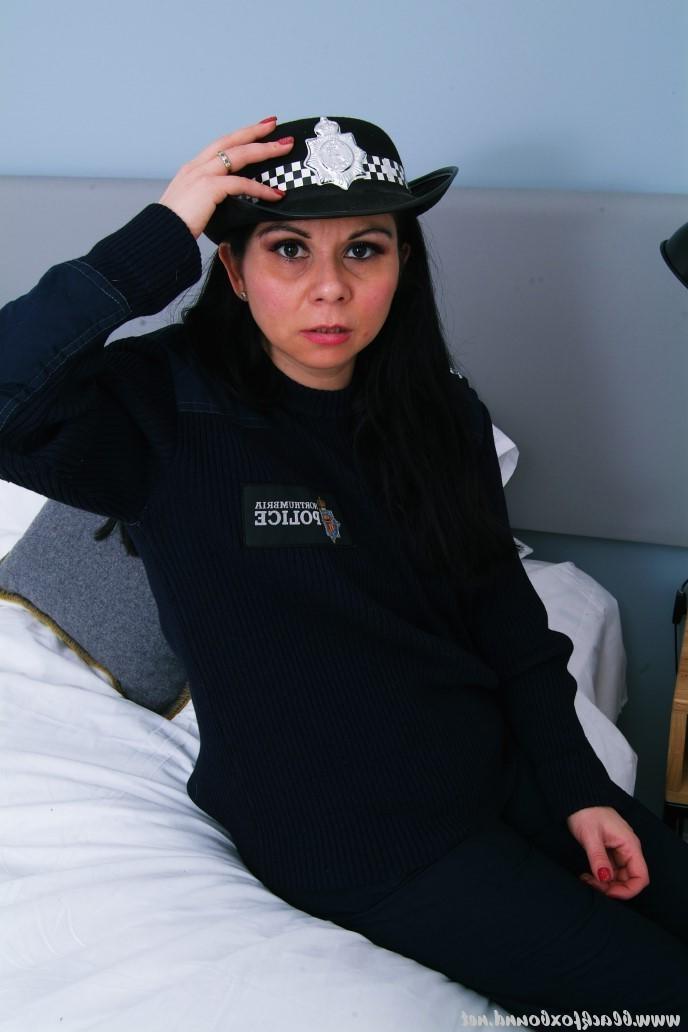 16P Mujer policía de cabello oscuro se encuentra atada a una silla con su uniforme