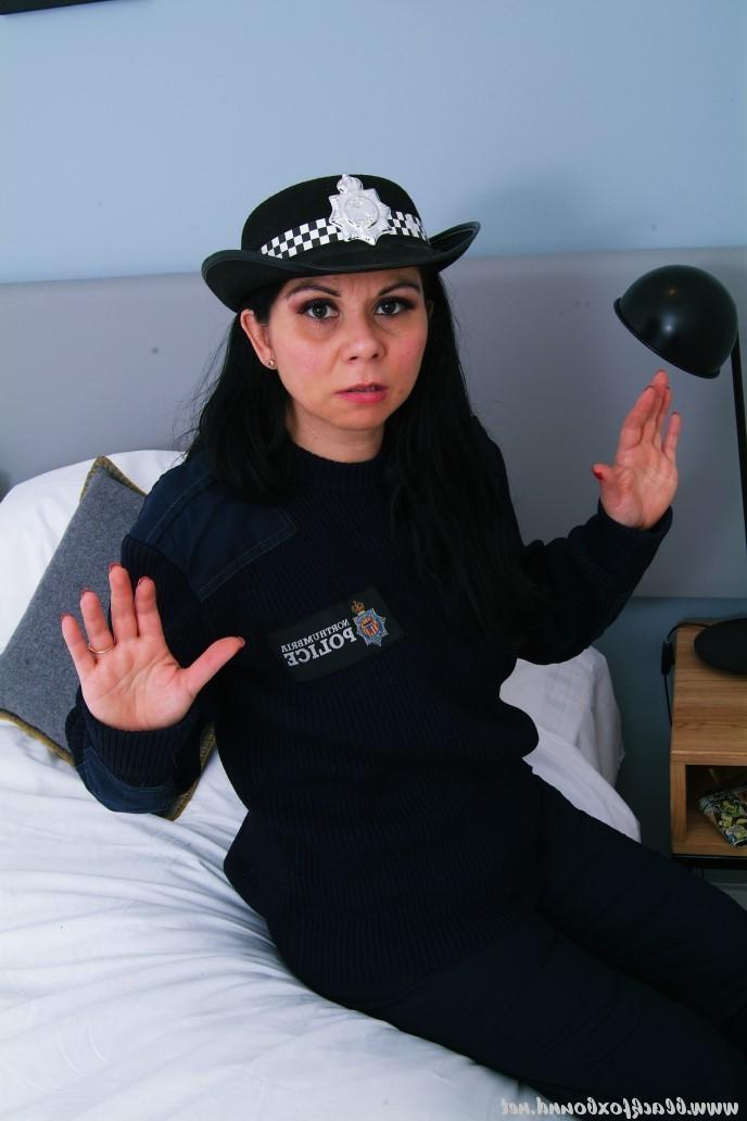 16P Mujer policía de cabello oscuro se encuentra atada a una silla con su uniforme