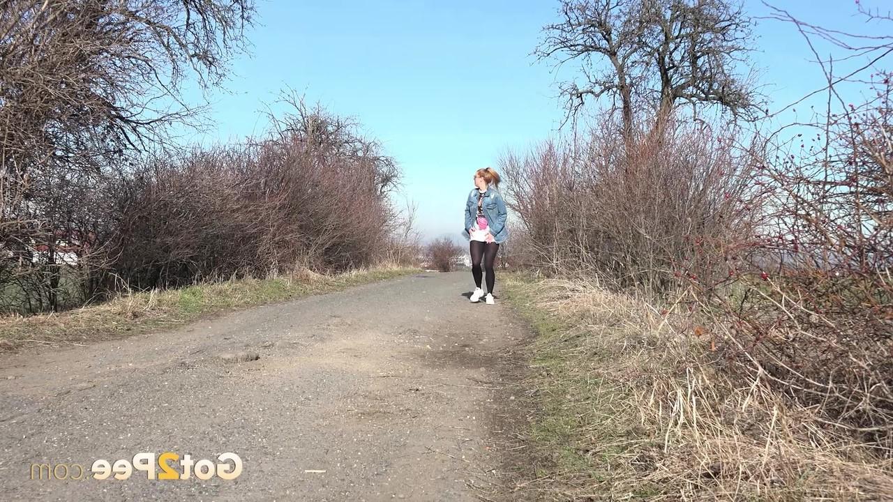 15P La chica blanca Chrissy Fox se baja las mallas negras para orinar en un camino de tierra
