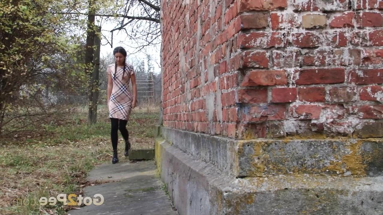 15P Garota legal puxa meia-calça preta para fazer xixi rápido atrás de um prédio