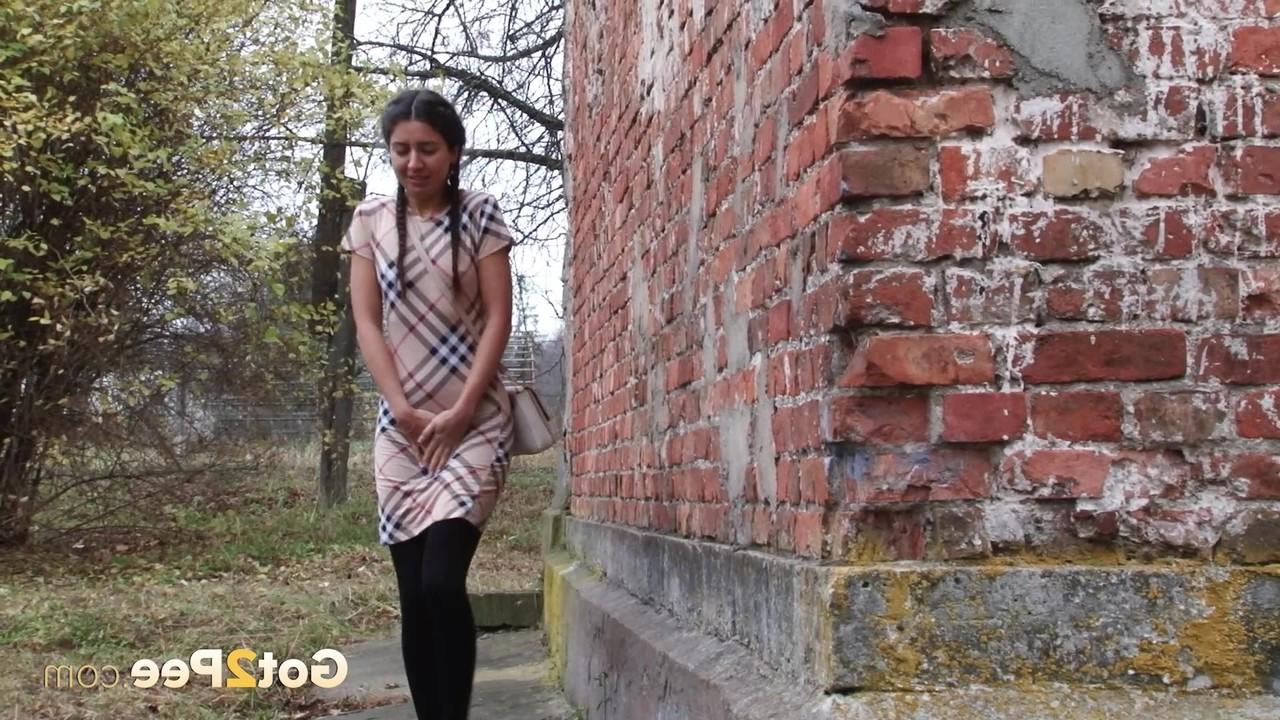 15P Garota legal puxa meia-calça preta para fazer xixi rápido atrás de um prédio