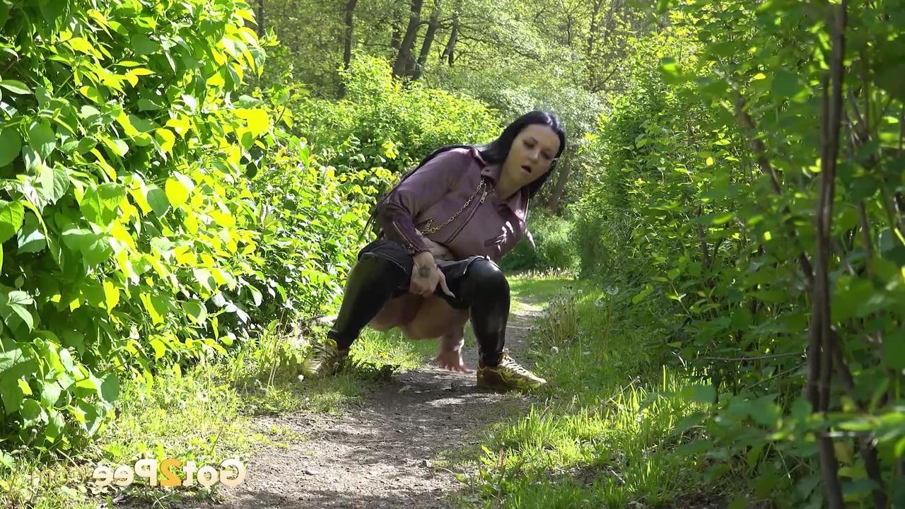 15P Pretty girl Isabel Dark pulls down her pants to pee on a path in the woods