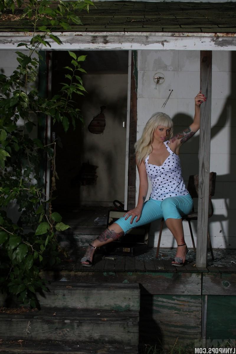 15P Die sexy Blondine mit Tätowierungen Lynn Pops zieht sich hinter einem verlassenen Haus aus