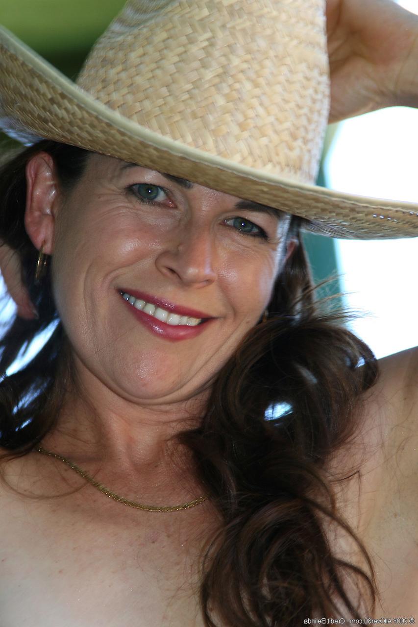 20P Cowgirl mature Andie montre ses petits seins et sa chatte poilue en extérieur.