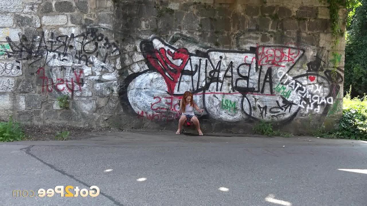15P Redheaded girl Foxie T takes a pee under an overpass during the day