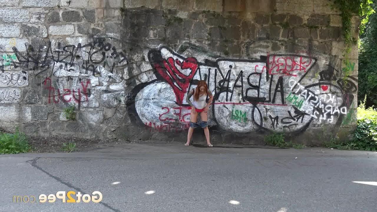 15P Redheaded girl Foxie T takes a pee under an overpass during the day