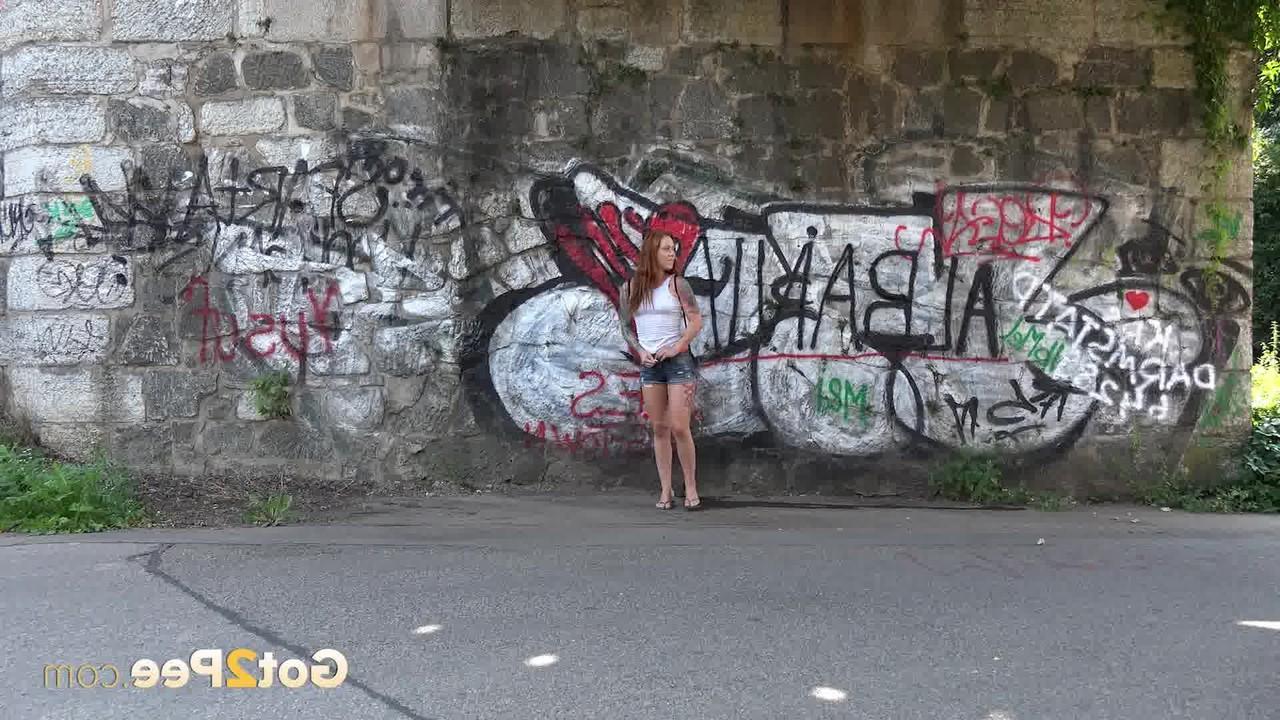 15P Redheaded girl Foxie T takes a pee under an overpass during the day