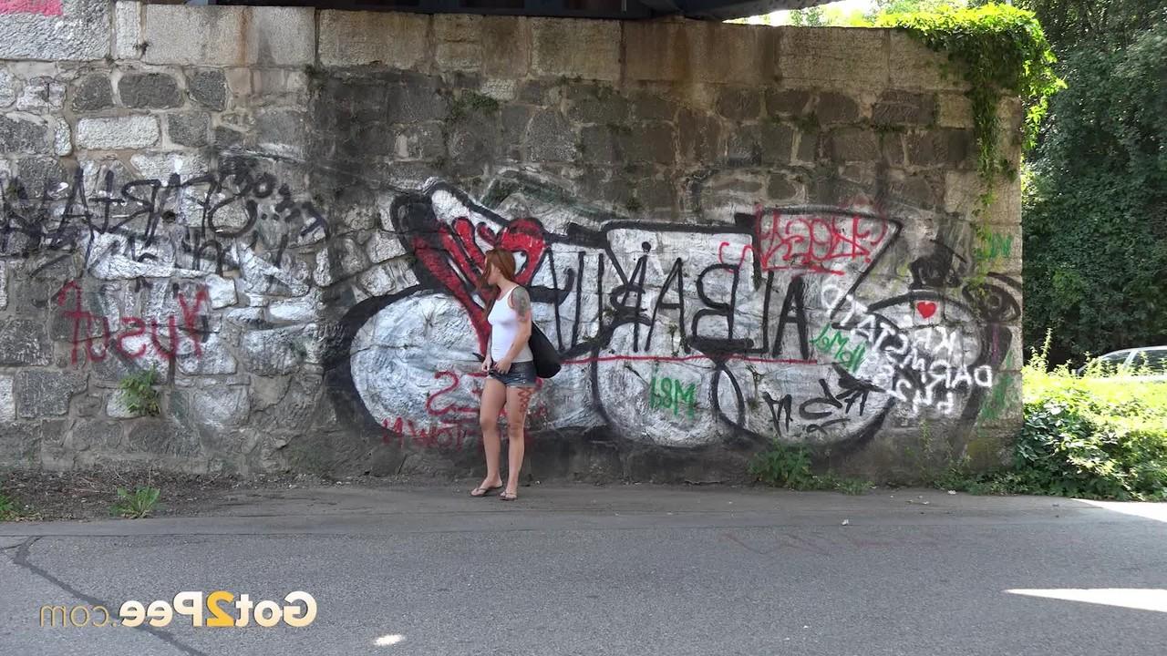 15P Redheaded girl Foxie T takes a pee under an overpass during the day