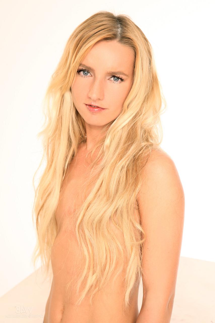 20P La jeune blonde Megann expose ses petits seins et sa chatte taillée en solo.