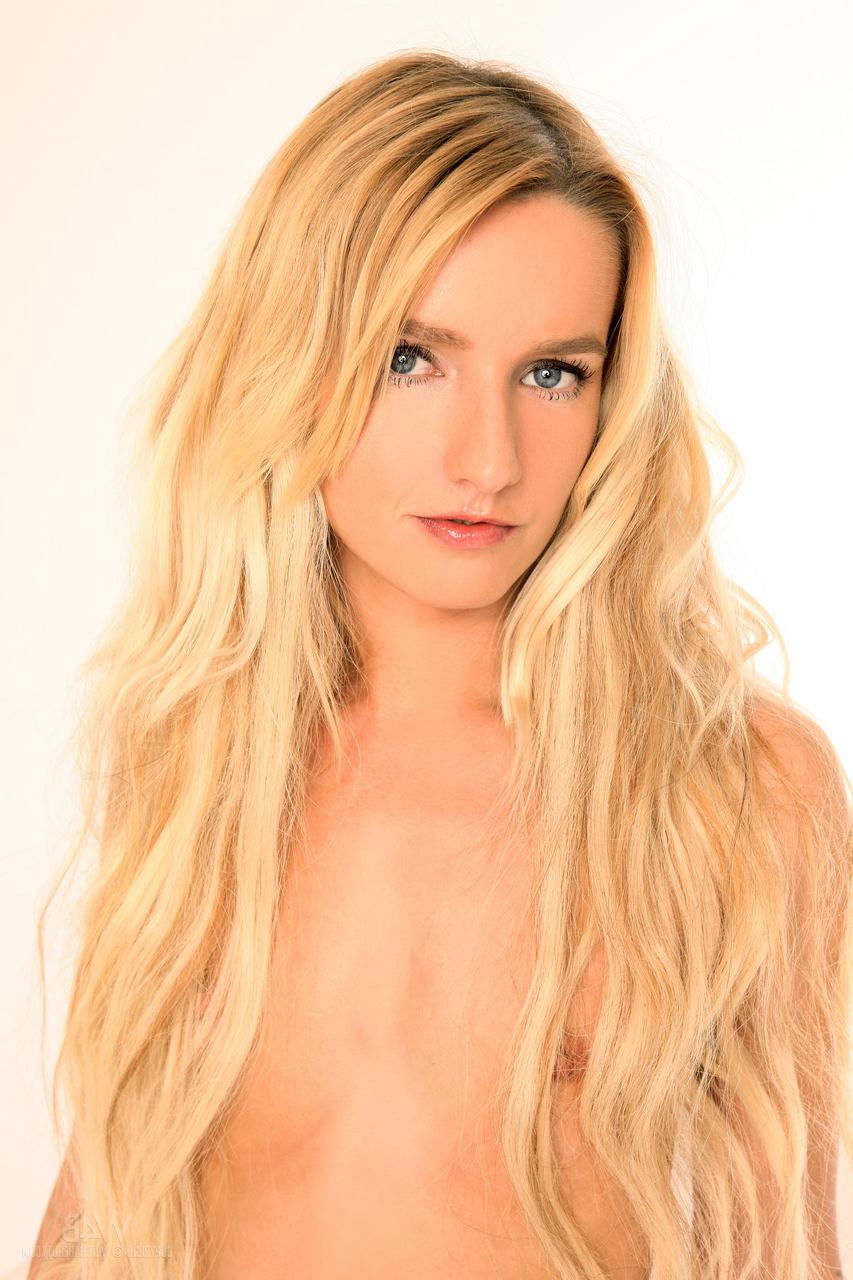 20P La jeune blonde Megann expose ses petits seins et sa chatte taillée en solo.