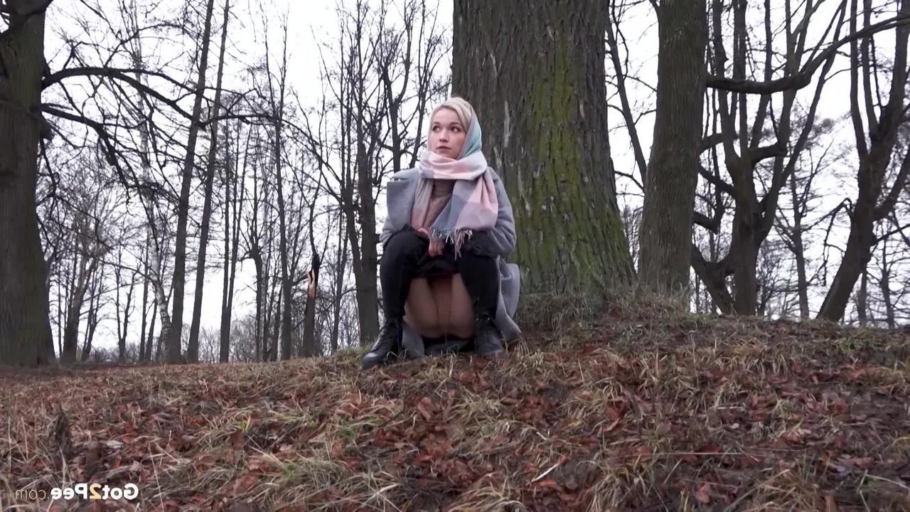15P Das blonde Mädchen Masha pinkelt an einem kühlen Tag vor einem Baum