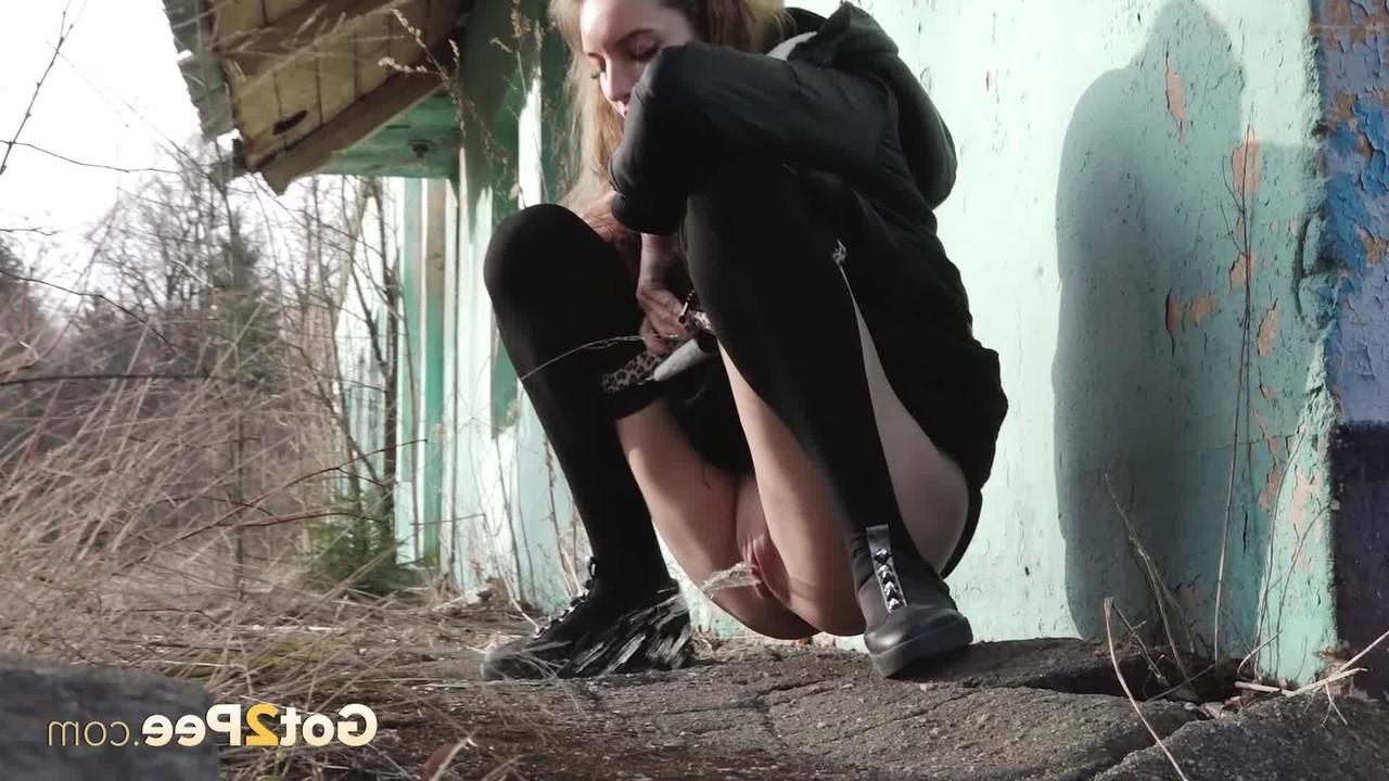 15P Garota sozinha puxa a mangueira preta antes de se agachar para fazer xixi ao lado de um prédio